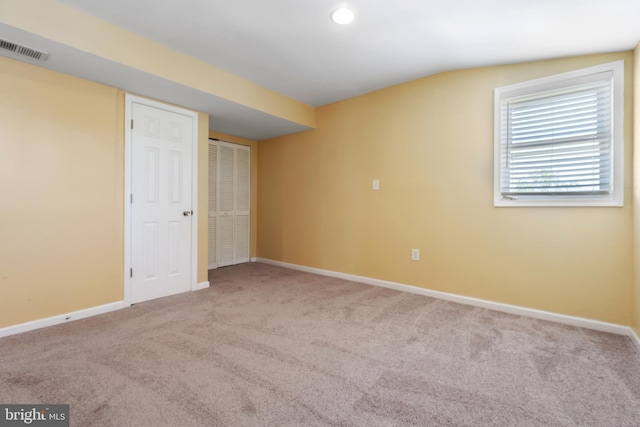 unfurnished bedroom with baseboards, visible vents, carpet floors, and vaulted ceiling