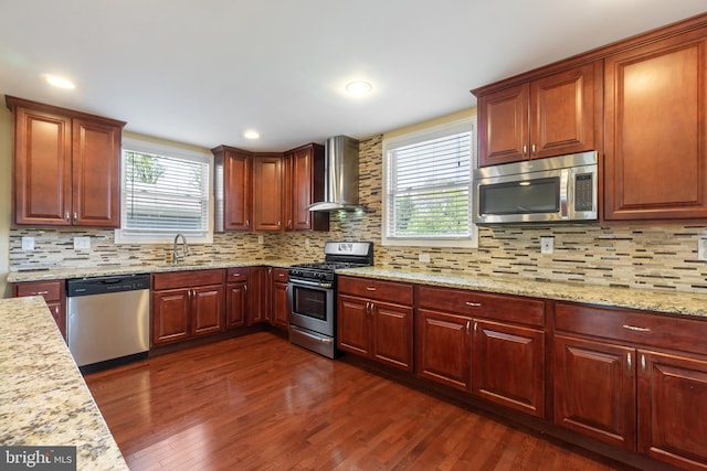 kitchen featuring a sink, stainless steel appliances, a healthy amount of sunlight, and wall chimney exhaust hood