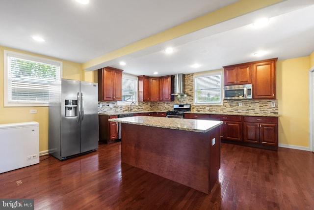 kitchen with dark wood-style floors, stainless steel appliances, tasteful backsplash, and wall chimney exhaust hood