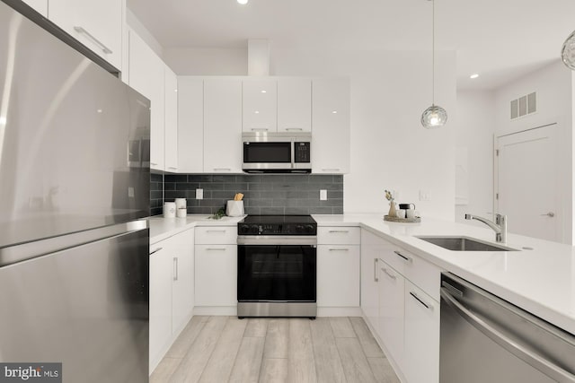 1001 Rhode Island Ave NE Unit 204, Washington, DC 20018 - kitchen with appliances with stainless steel finishes, a sink, light countertops, white cabinetry, and decorative backsplash