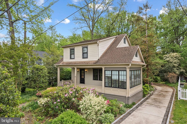 view of front of property featuring driveway, roof with shingles, covered porch, fence, and view of scattered trees