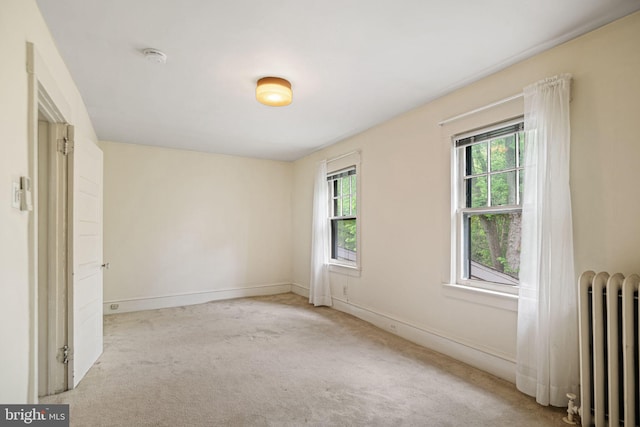 carpeted spare room with radiator heating unit, healthy amount of natural light, and baseboards