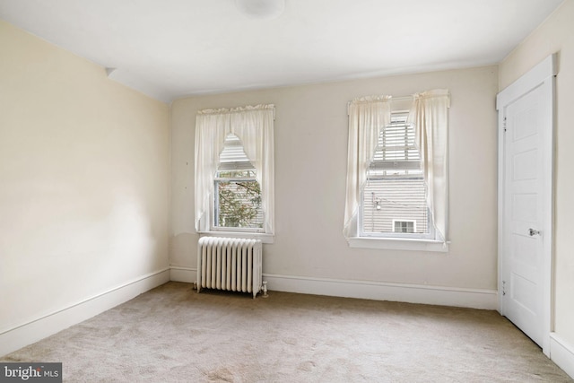 empty room featuring radiator, plenty of natural light, carpet, and baseboards
