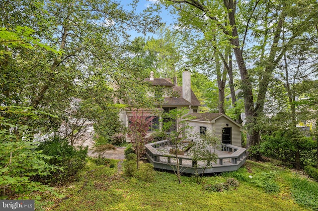 rear view of house featuring a wooden deck and a chimney