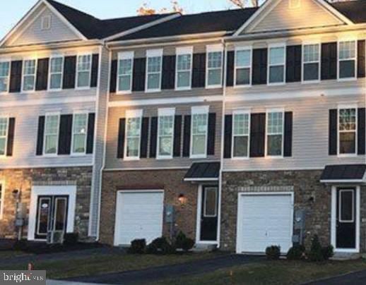multi unit property with stone siding and a garage