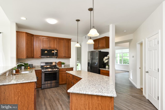 kitchen with stainless steel appliances, a sink, dark wood-style flooring, a kitchen island, and decorative backsplash