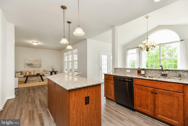 kitchen featuring black dishwasher, a sink, a center island, light wood finished floors, and light stone countertops