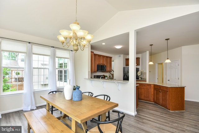 dining space featuring a chandelier, wood finished floors, lofted ceiling, and baseboards