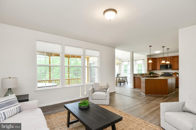 living room featuring dark wood-type flooring, baseboards, and a chandelier