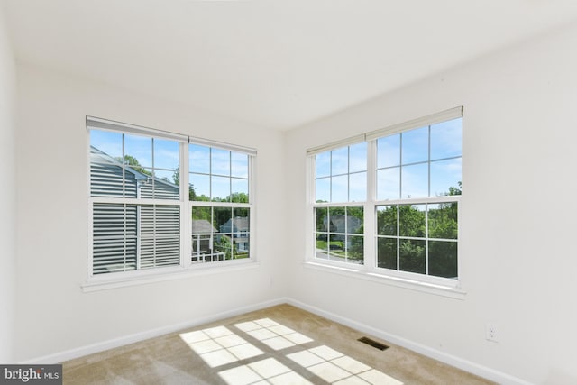 spare room with light colored carpet and baseboards