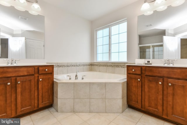 full bath featuring a bath, a shower stall, two vanities, and tile patterned floors