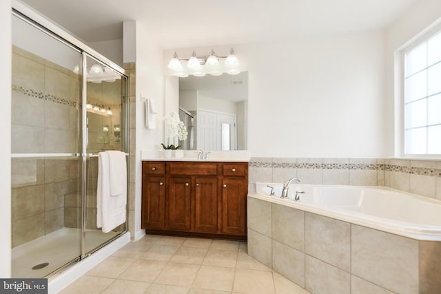 bathroom featuring tile patterned flooring, a stall shower, a garden tub, and vanity