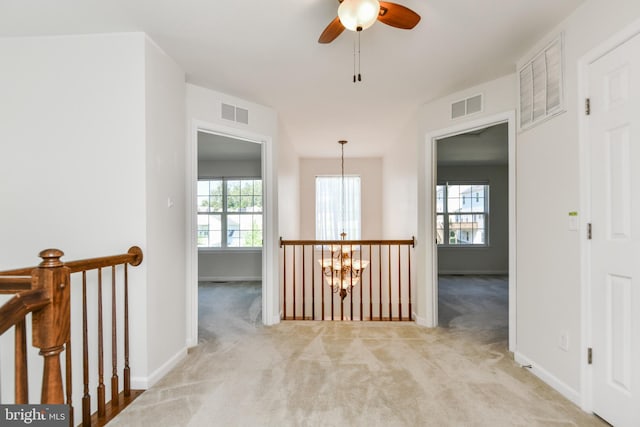 hallway with a chandelier, light carpet, an upstairs landing, and baseboards
