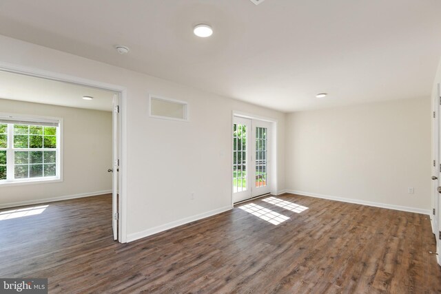 spare room featuring plenty of natural light, dark wood-style floors, and baseboards