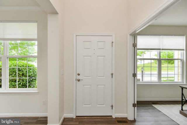 foyer entrance with dark wood finished floors, crown molding, and baseboards