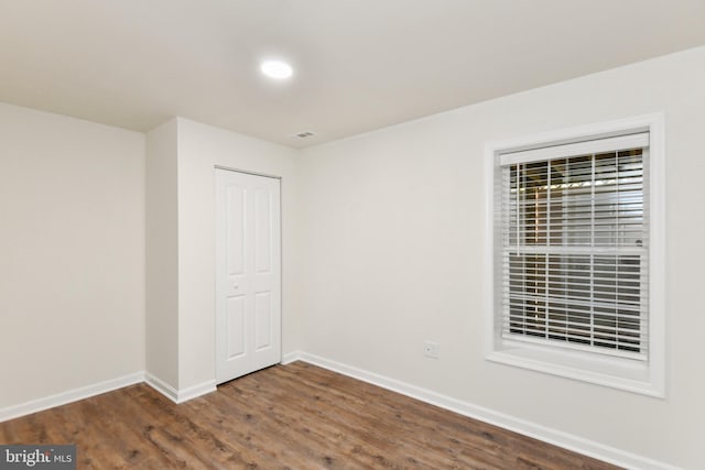 spare room with baseboards, dark wood finished floors, and recessed lighting