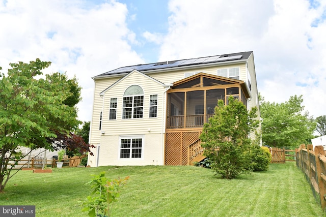 rear view of property featuring a sunroom and solar panels