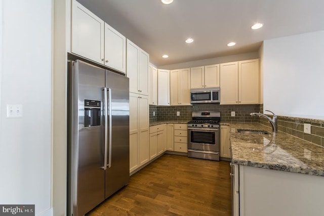 kitchen with appliances with stainless steel finishes, decorative backsplash, light stone countertops, and a sink