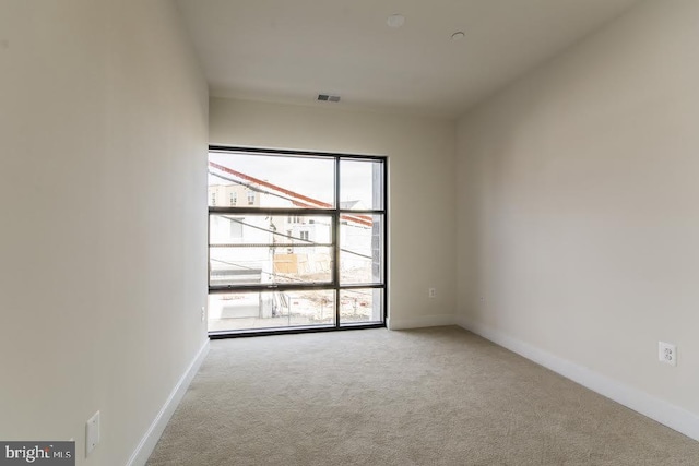 spare room featuring baseboards, visible vents, and carpet