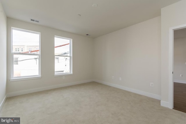 unfurnished room with baseboards, light carpet, and visible vents