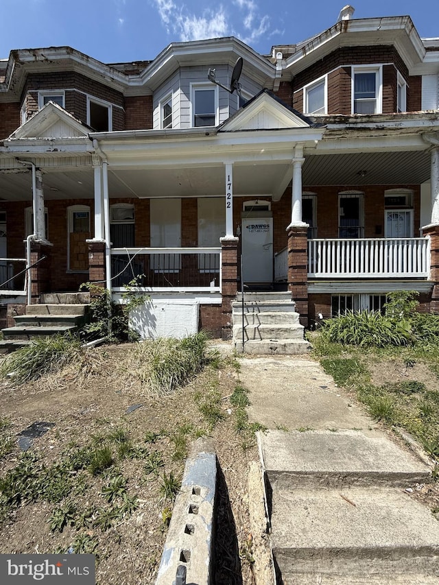 view of property featuring a porch and brick siding