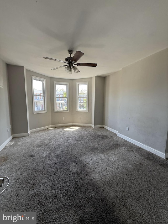 empty room featuring carpet flooring, baseboards, and a ceiling fan