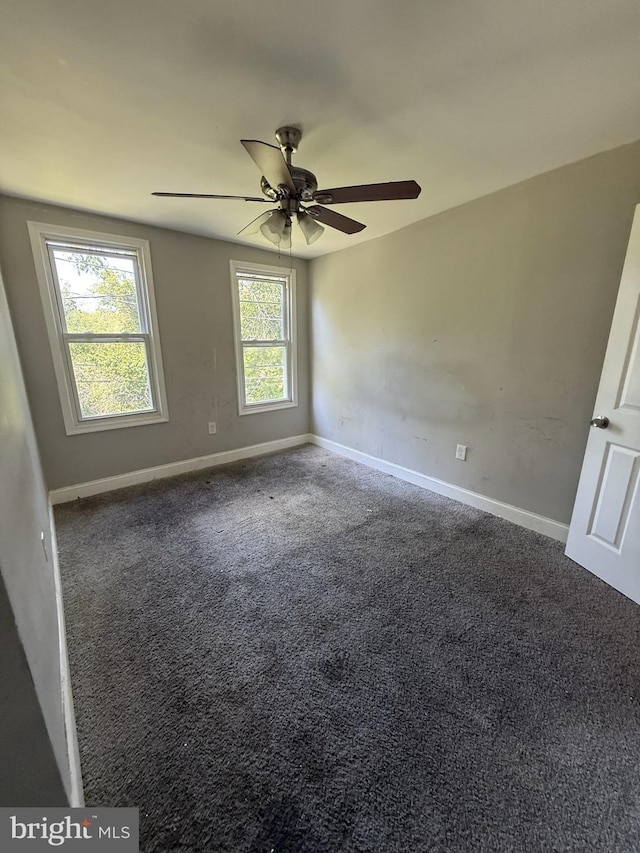 empty room featuring carpet, baseboards, and a ceiling fan