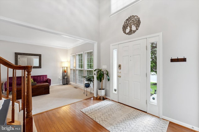 entryway featuring baseboards, stairs, hardwood / wood-style flooring, and crown molding