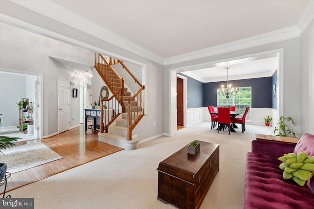 living area with carpet floors, crown molding, stairs, a chandelier, and wainscoting