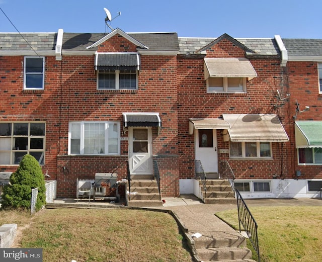 view of front of house featuring entry steps, a front lawn, and brick siding