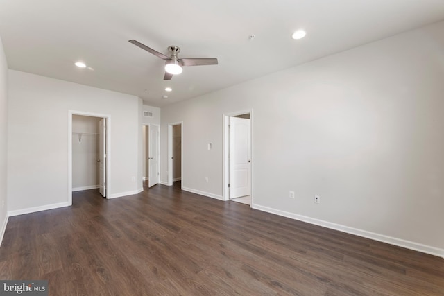 unfurnished bedroom featuring dark wood-type flooring, a spacious closet, baseboards, recessed lighting, and ceiling fan