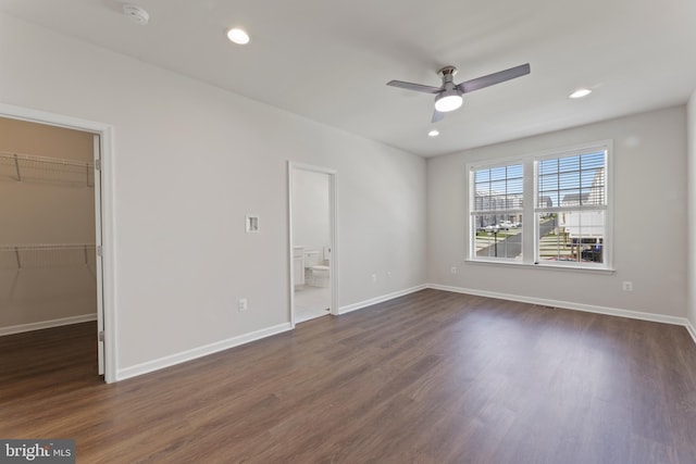 unfurnished bedroom with a spacious closet, dark wood-type flooring, baseboards, recessed lighting, and ensuite bathroom
