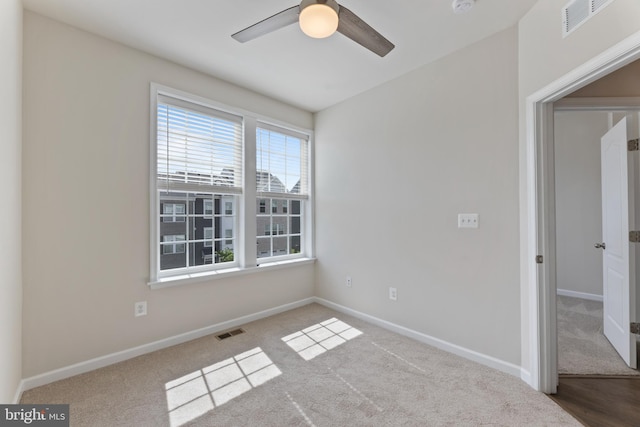 carpeted empty room with ceiling fan and baseboards