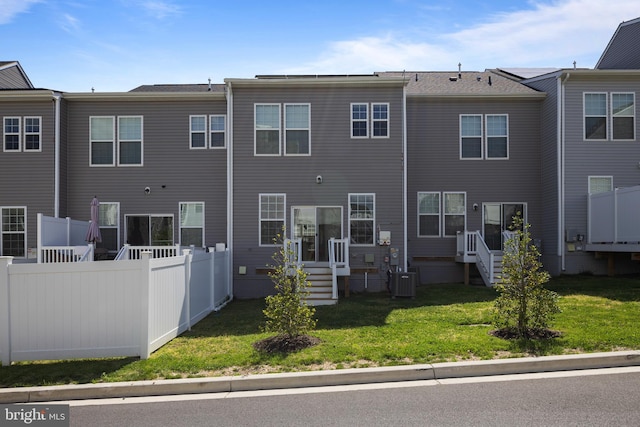 back of house with a lawn, central air condition unit, and fence