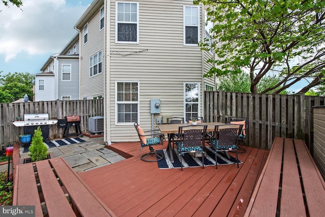 wooden deck with central AC, outdoor dining area, a grill, and fence