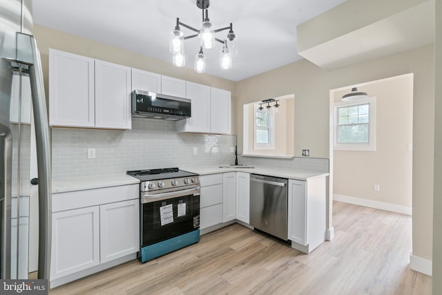 2701 Christopher Ave, Baltimore, MD 21214 - kitchen featuring appliances with stainless steel finishes, a chandelier, decorative backsplash, light countertops, and light wood finished floors