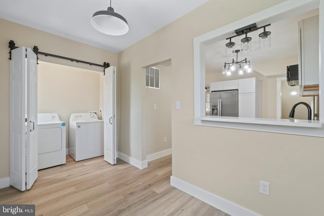 2701 Christopher Ave, Baltimore, MD 21214 - laundry area with washer and clothes dryer, a barn door, and light wood-type flooring