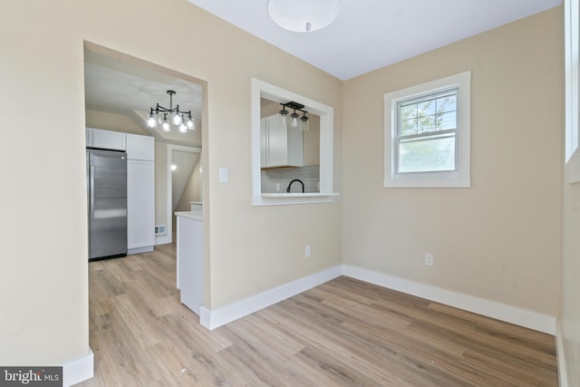 2701 Christopher Ave, Baltimore, MD 21214 - empty room with light wood finished floors and a chandelier