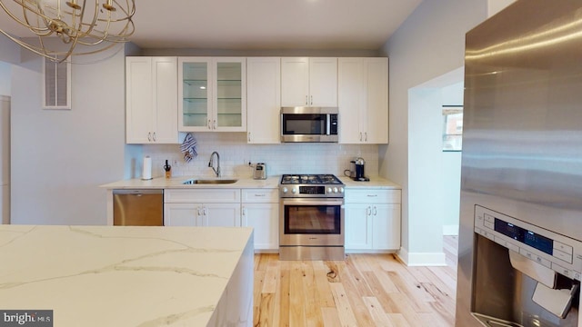 4914 3rd St NW, Washington, DC 20011 - kitchen featuring a sink, light wood-type flooring, white cabinets, a notable chandelier, and appliances with stainless steel finishes
