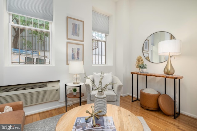 sitting room featuring a wall mounted AC, baseboards, and wood finished floors