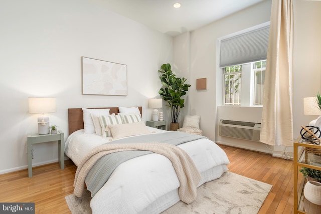 bedroom with baseboards, hardwood / wood-style floors, a wall mounted air conditioner, and recessed lighting