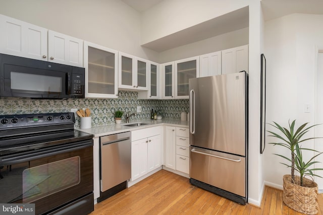 kitchen featuring decorative backsplash, black appliances, light countertops, white cabinets, and light wood-type flooring
