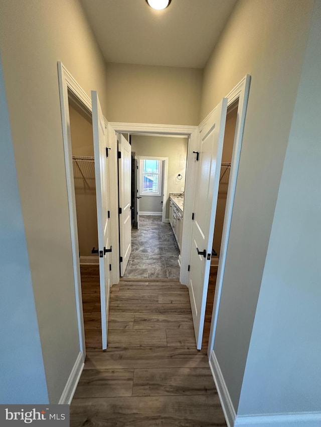 hallway featuring baseboards and dark wood finished floors