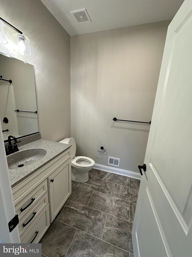 half bath featuring toilet, visible vents, baseboards, and vanity