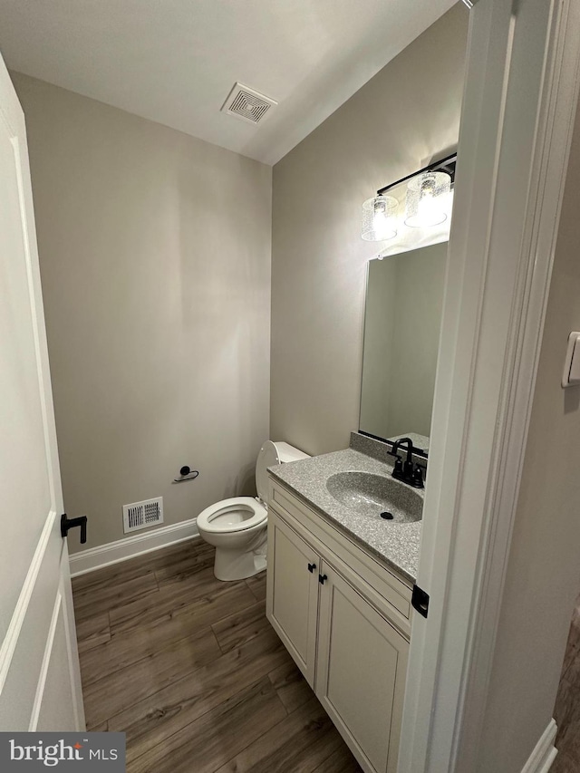 bathroom with vanity, toilet, visible vents, and wood finished floors