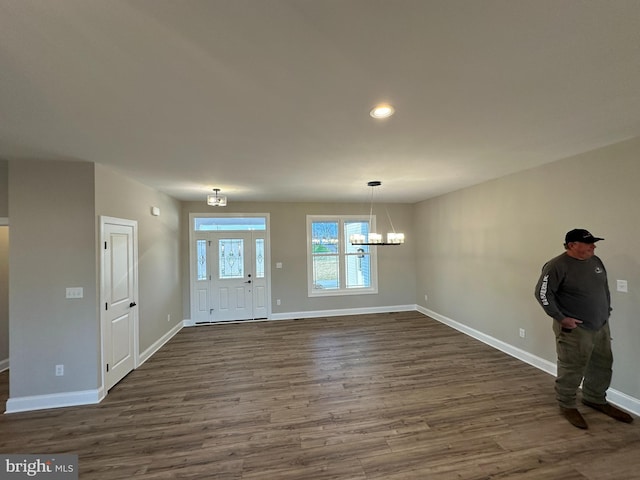 entrance foyer with dark wood finished floors, baseboards, and a notable chandelier