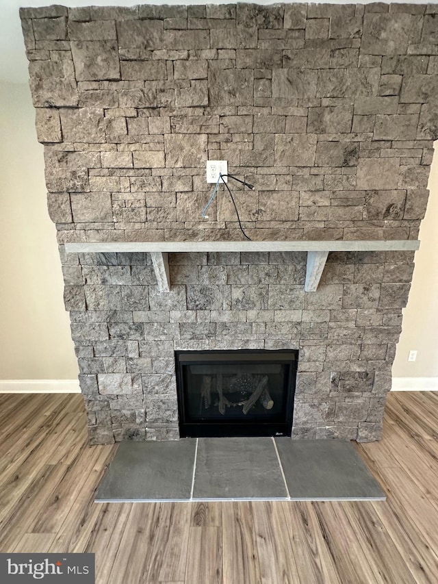 interior details with baseboards, a fireplace, and wood finished floors