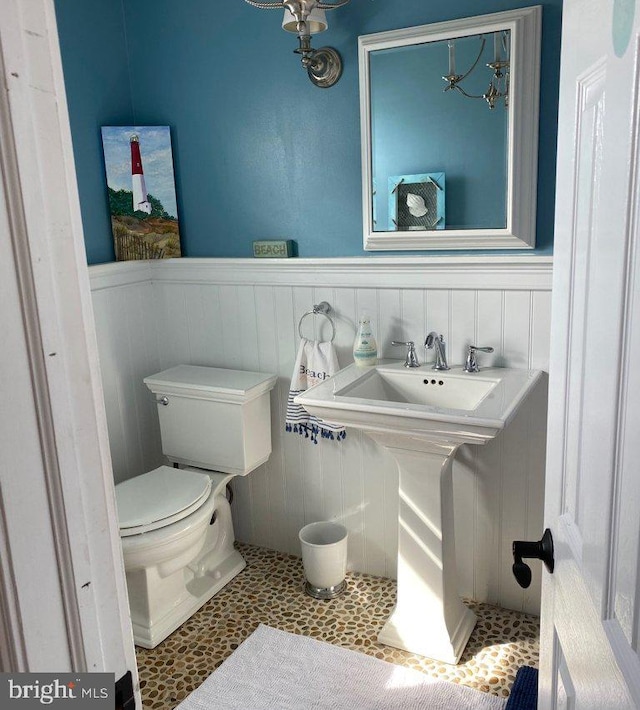 bathroom featuring a wainscoted wall, toilet, and tile patterned flooring