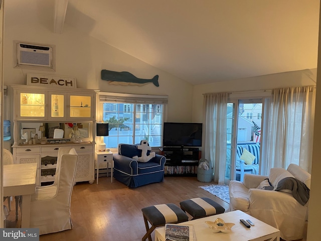 living room with lofted ceiling, light wood finished floors, healthy amount of natural light, and a wall mounted air conditioner