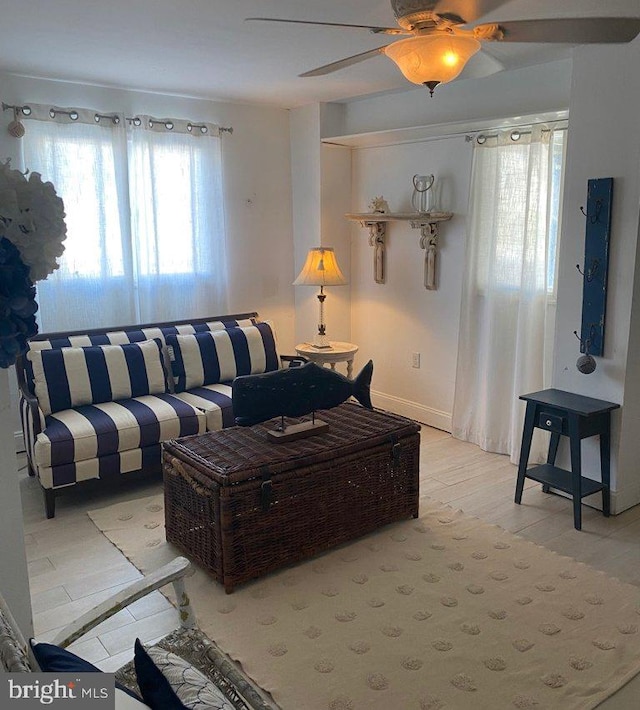 living area featuring ceiling fan, light wood finished floors, and a healthy amount of sunlight